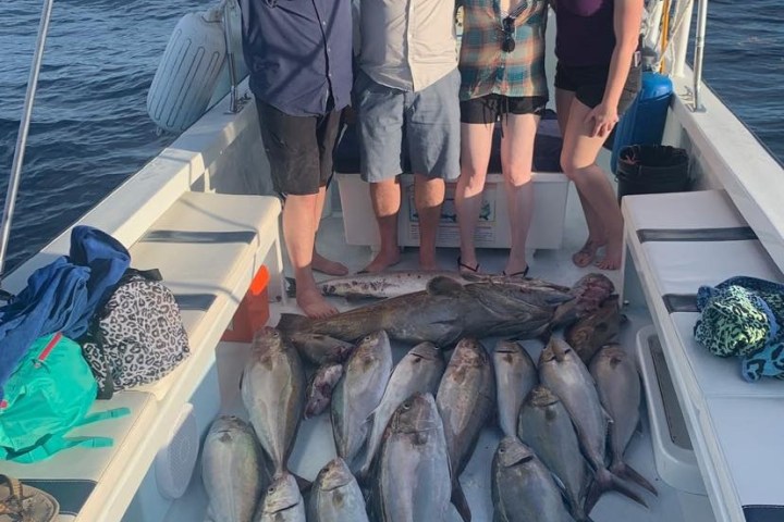 a group of people posing for a fish on a boat