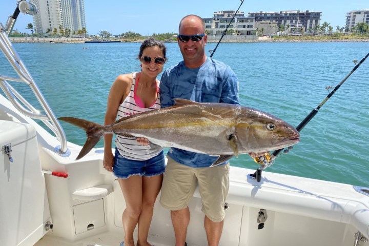 a man holding a fish on a boat in the water