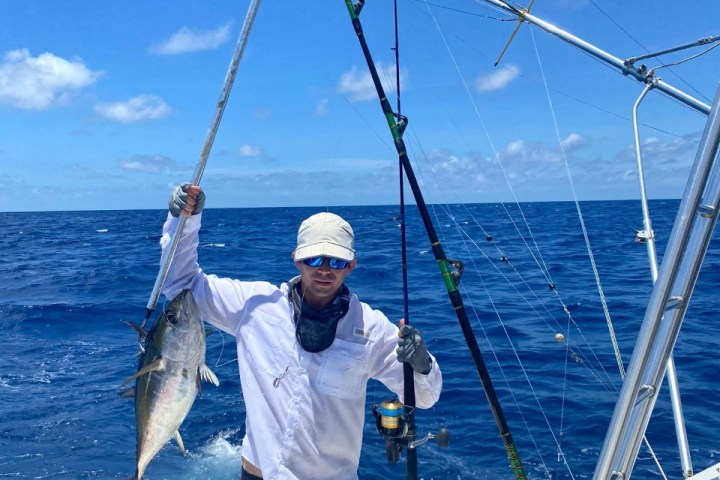 a man holding a fish on a boat