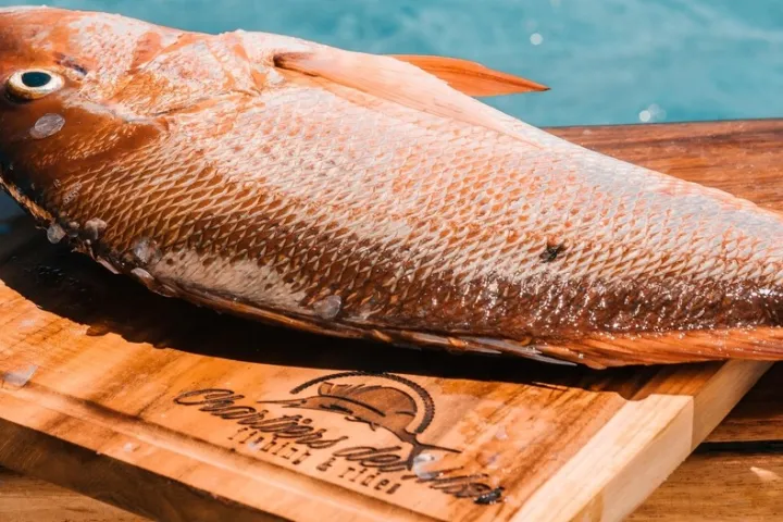 a fish sitting on top of a wooden cutting board