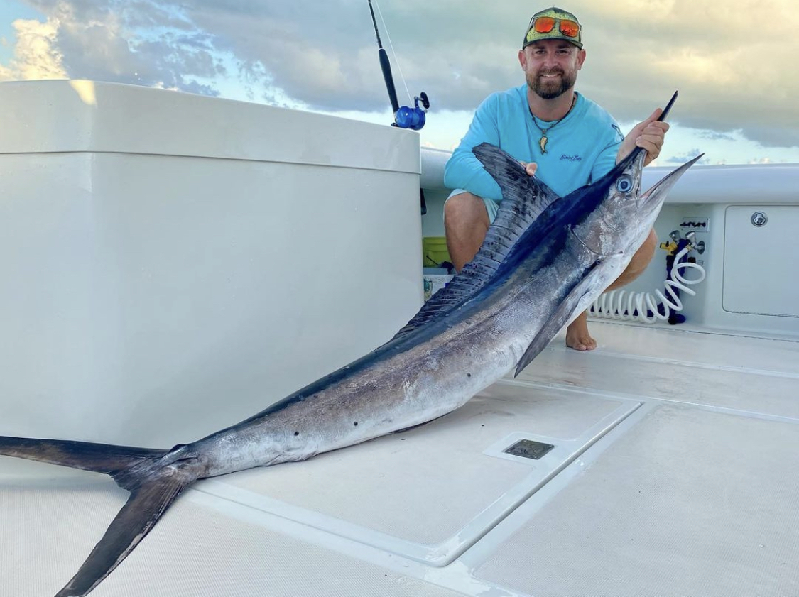 Marlin Captain Travis in Cancún holding a large White Marlin on a fishing boa